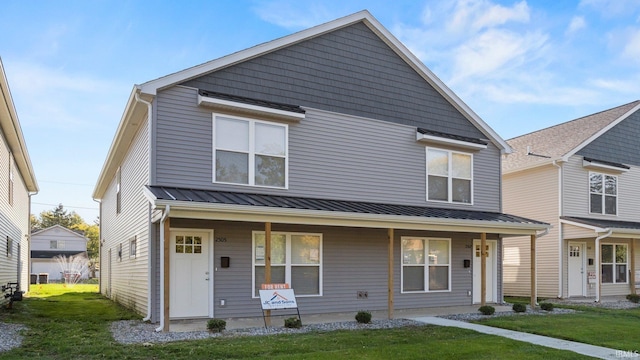 view of front of house featuring a porch, a front yard, a standing seam roof, and metal roof