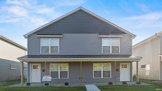 view of front of house with a front lawn, covered porch, and a standing seam roof