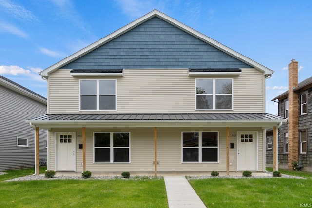 view of front of property featuring covered porch, metal roof, a front lawn, and a standing seam roof