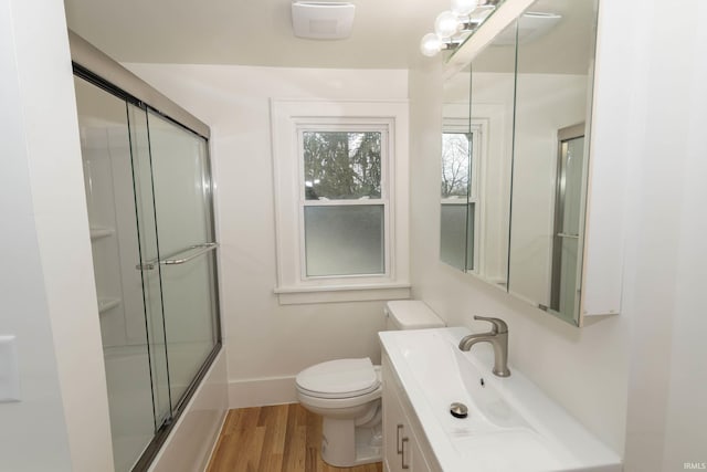 full bath featuring toilet, combined bath / shower with glass door, vanity, wood finished floors, and baseboards