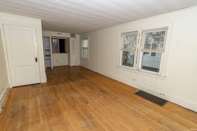 empty room featuring baseboards, visible vents, and light wood finished floors