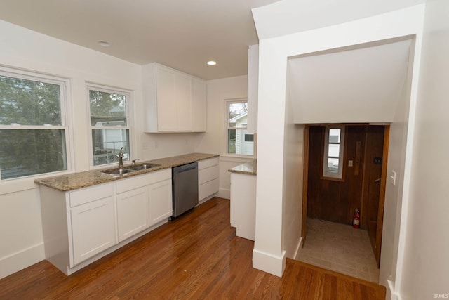 kitchen with white cabinets, dishwasher, light stone counters, wood finished floors, and a sink