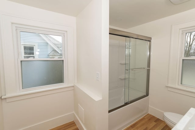 full bathroom featuring toilet, enclosed tub / shower combo, baseboards, and wood finished floors