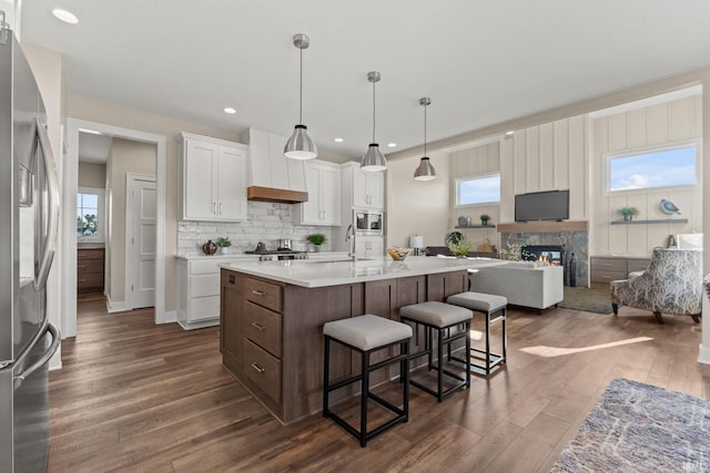 kitchen with dark wood-style flooring, a breakfast bar area, light countertops, appliances with stainless steel finishes, and open floor plan