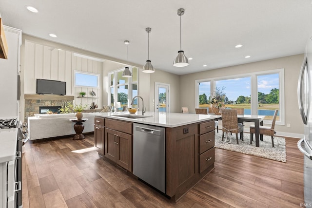 kitchen featuring stainless steel appliances, a sink, light countertops, a wealth of natural light, and dark wood-style floors