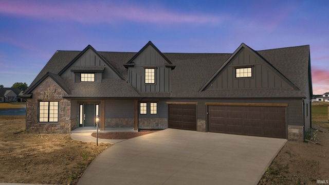 view of front of home featuring driveway, stone siding, a shingled roof, and board and batten siding