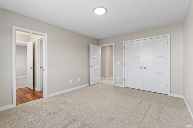 unfurnished bedroom featuring carpet, baseboards, and a closet