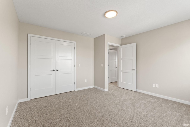 unfurnished bedroom featuring a textured ceiling, a closet, baseboards, and carpet flooring