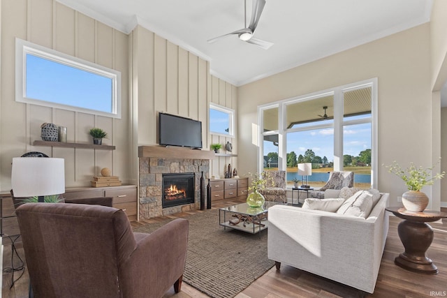 living area with ceiling fan, a fireplace, wood finished floors, and crown molding