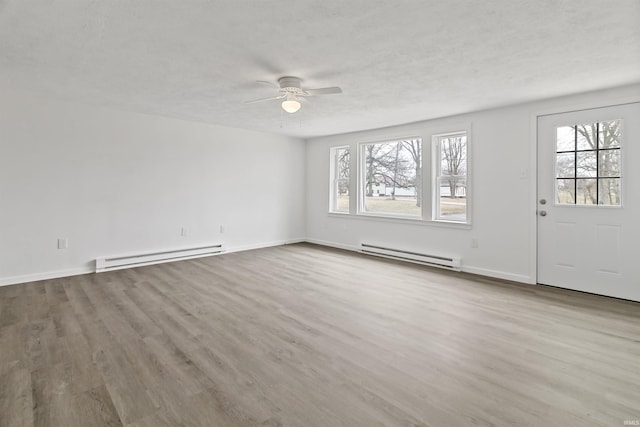 interior space featuring a ceiling fan, a textured ceiling, baseboard heating, and wood finished floors