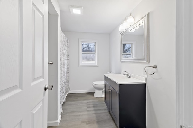 bathroom featuring toilet, a shower with shower curtain, wood finished floors, vanity, and baseboards