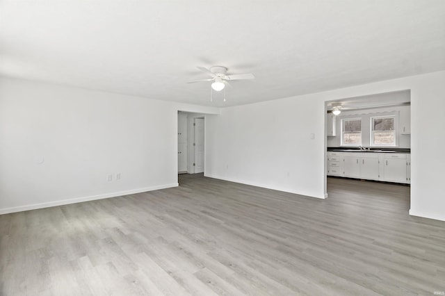 empty room featuring ceiling fan, baseboards, and wood finished floors