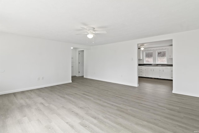 spare room featuring a sink, ceiling fan, baseboards, and wood finished floors