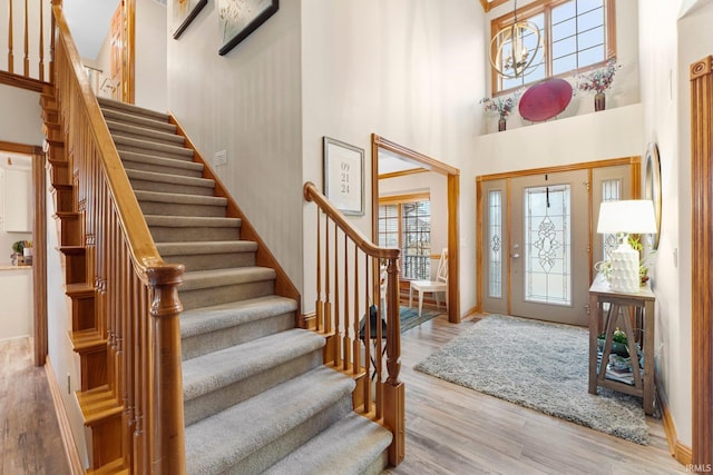 foyer entrance with an inviting chandelier, stairway, a high ceiling, and wood finished floors