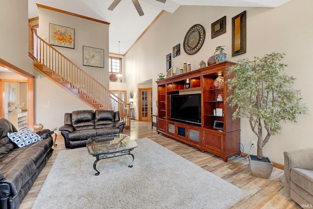 living room with light wood finished floors, ceiling fan, stairway, and high vaulted ceiling