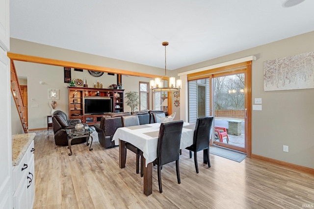 dining area featuring baseboards, an inviting chandelier, light wood-style flooring, and a healthy amount of sunlight