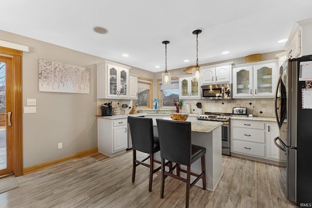 kitchen with light wood finished floors, tasteful backsplash, and stainless steel appliances