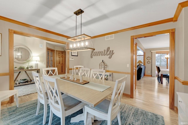 dining area featuring light wood-style floors, visible vents, crown molding, and baseboards