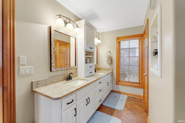 bathroom with visible vents, a sink, baseboards, and double vanity