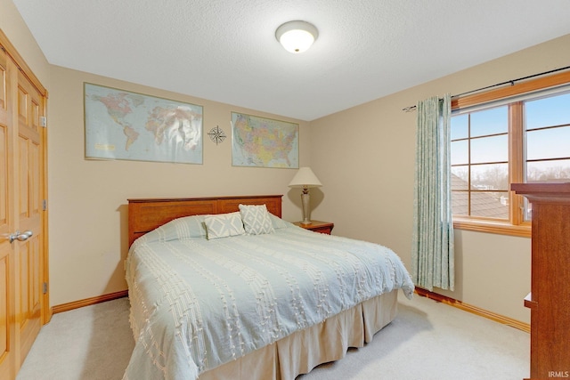 bedroom featuring light carpet, a textured ceiling, and baseboards