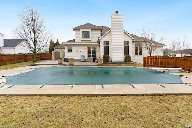 rear view of property with a patio, a storage unit, an outdoor structure, and a fenced backyard