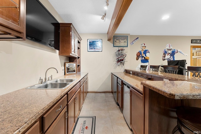 kitchen with rail lighting, light tile patterned flooring, a sink, a peninsula, and a kitchen breakfast bar