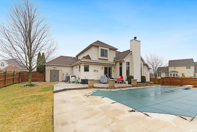 rear view of house featuring a patio, a fenced backyard, a storage shed, an outdoor structure, and a lawn