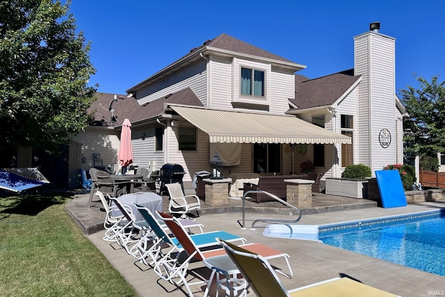 rear view of property with a patio, roof with shingles, a chimney, and an outdoor pool