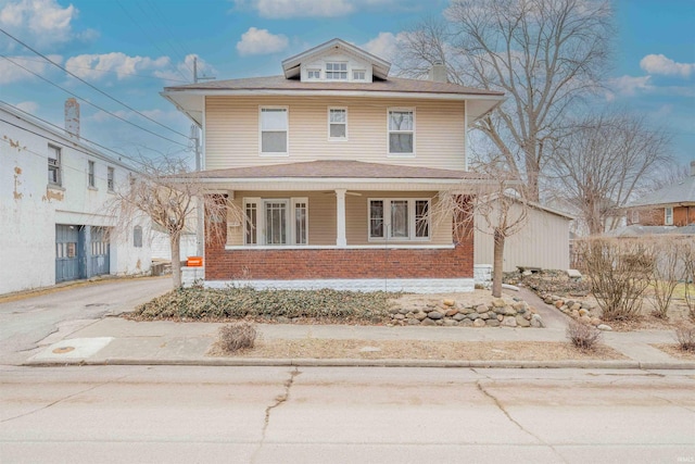 traditional style home with a porch, a chimney, aphalt driveway, and brick siding