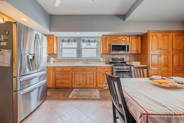 kitchen with light countertops, appliances with stainless steel finishes, a sink, and tasteful backsplash