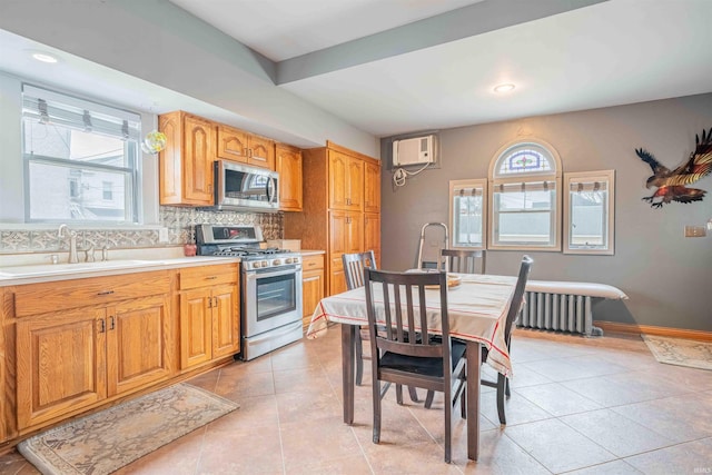 kitchen with appliances with stainless steel finishes, a healthy amount of sunlight, decorative backsplash, and radiator heating unit