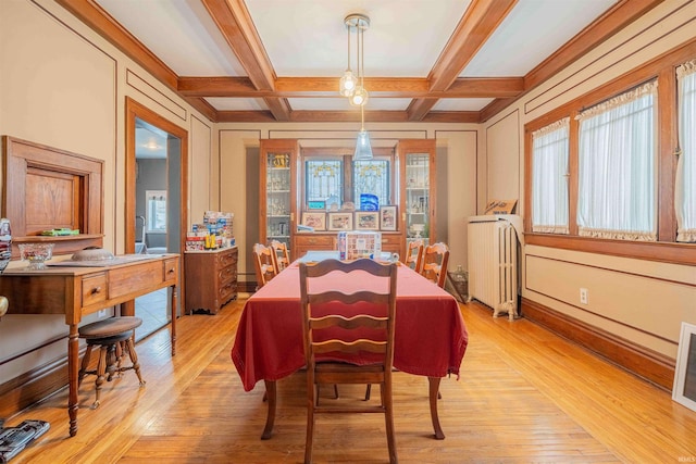 dining space featuring radiator, light wood-style flooring, coffered ceiling, and a wealth of natural light