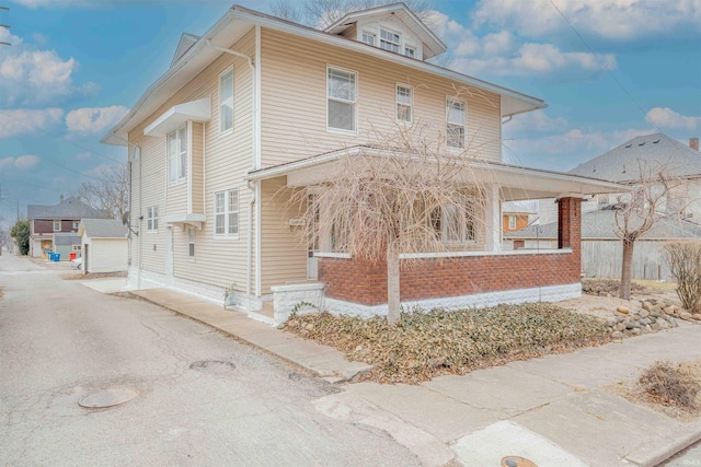 view of front facade featuring a porch, an outdoor structure, a detached garage, and aphalt driveway