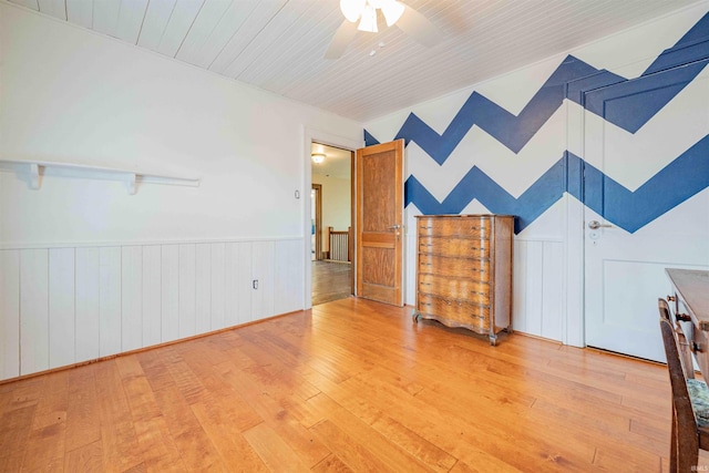 interior space featuring a ceiling fan, wood ceiling, wainscoting, and hardwood / wood-style flooring