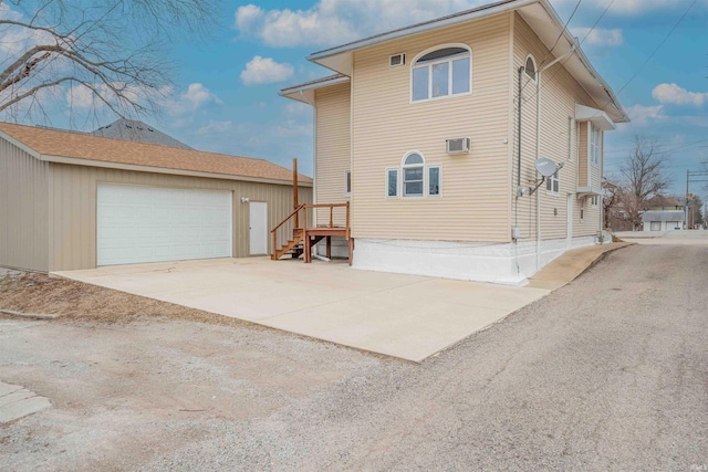 exterior space featuring an outbuilding, an AC wall unit, and a detached garage