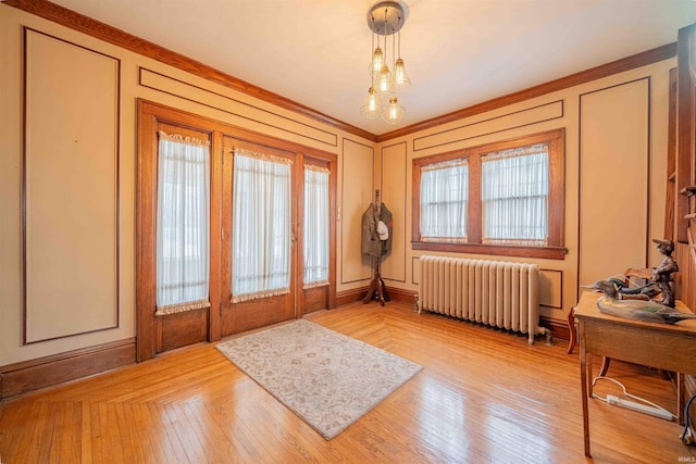 entrance foyer with radiator heating unit, light wood-style flooring, and a decorative wall