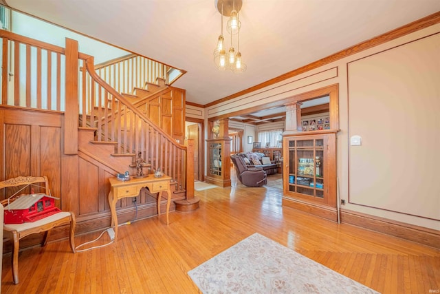 entrance foyer featuring wooden walls, stairway, hardwood / wood-style floors, decorative columns, and crown molding