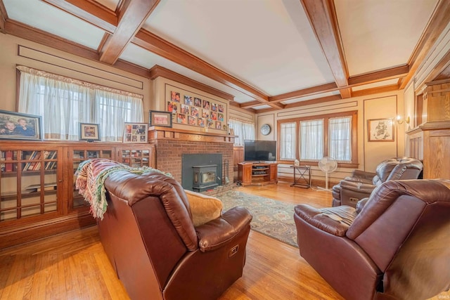 living room featuring a wood stove, beam ceiling, coffered ceiling, and light wood-style flooring