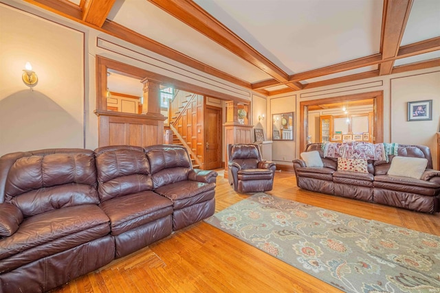 living room with beam ceiling, coffered ceiling, stairway, and wood finished floors