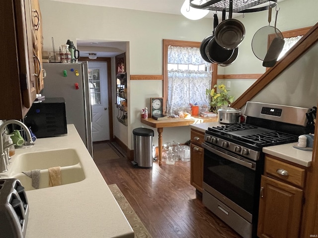 kitchen featuring appliances with stainless steel finishes, dark wood-type flooring, a sink, and light countertops