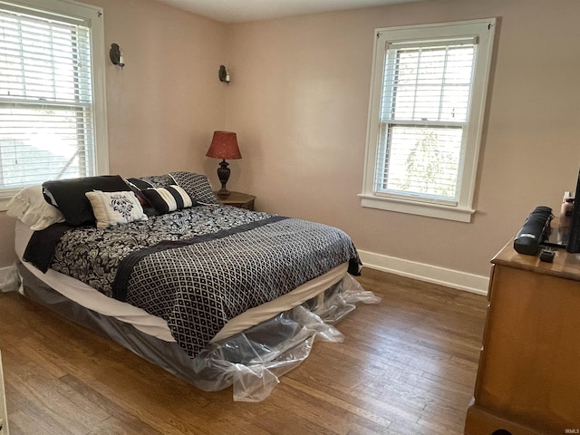 bedroom with multiple windows, baseboards, and wood finished floors