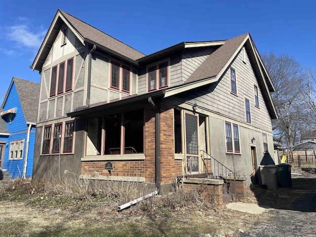 view of home's exterior featuring brick siding, roof with shingles, and stucco siding