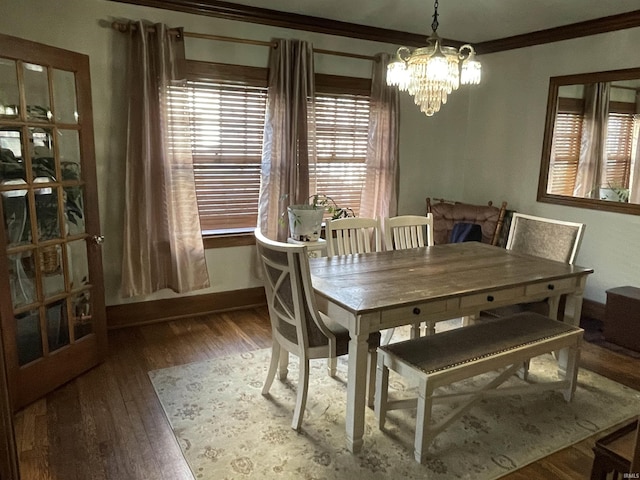 dining space with a chandelier, crown molding, baseboards, and wood finished floors