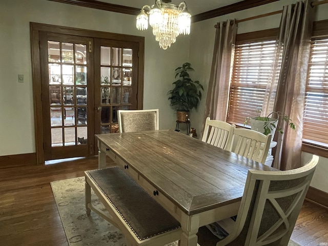 dining space featuring an inviting chandelier, baseboards, wood finished floors, and ornamental molding