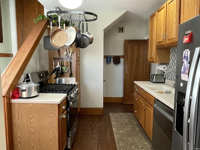 kitchen featuring appliances with stainless steel finishes, brown cabinets, dark wood-type flooring, light countertops, and a sink