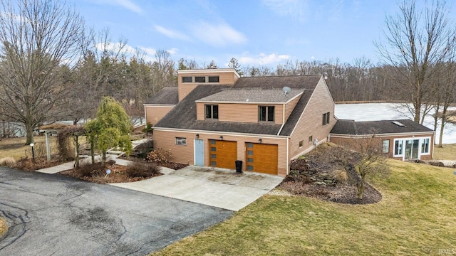 view of front of home with roof with shingles, aphalt driveway, a front lawn, and an attached garage