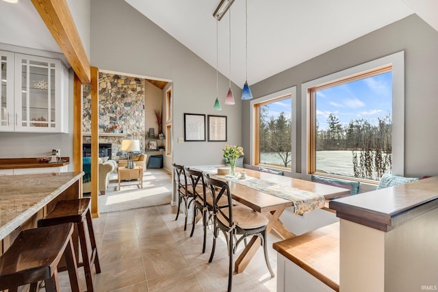 dining space featuring a fireplace and high vaulted ceiling