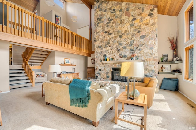 carpeted living room featuring baseboards, visible vents, wood ceiling, stairway, and a fireplace