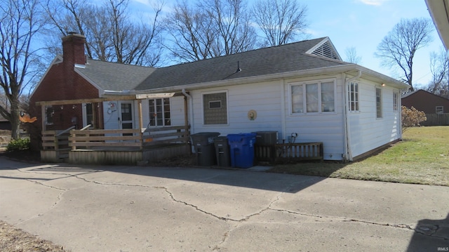 view of front of home featuring a shingled roof, a chimney, and a wooden deck