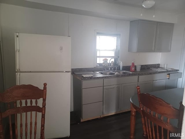 kitchen featuring freestanding refrigerator, a sink, and dark countertops